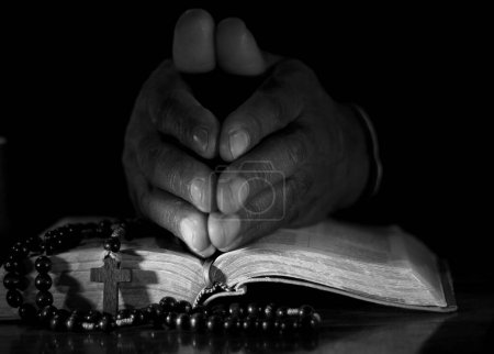 Foto de Hombre rezando a Dios con las manos en la Biblia - Imagen libre de derechos