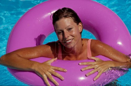 Jeune femme avec anneau de natation en piscine