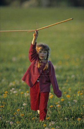 Kleiner Junge spielt mit Mädchen mit Segelflugzeug, Spielzeug auf einer Wiese