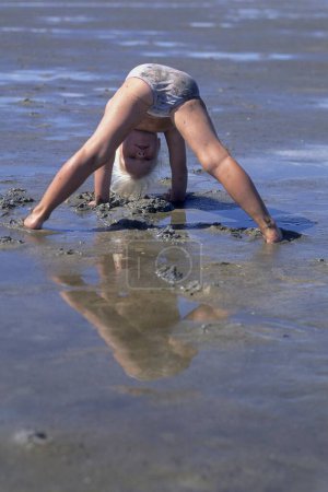 Petite fille faisant de la gymnastique sur la plage de sable