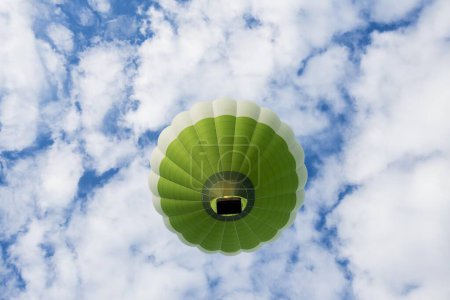 Green hot air balloon in front of blue sky with clouds, France, Europe