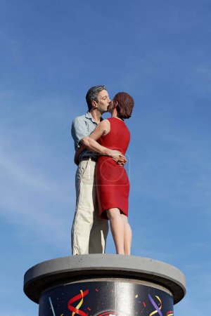 Kissing couple on an advertising pillar in front of a blue sky, realistic sculpture by Christoph Pggeler, Dsseldorf, North Rhine-Westphalia, Germany, Europe 