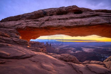 View through arch Mesa Arch at sunrise, Colorado River Canyon with the La Sal Mountains behind