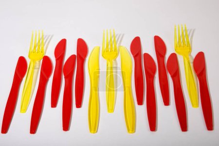 Cubiertos de plástico rojo y amarillo, cuchillos de plástico, tenedores de plástico, residuos de plástico