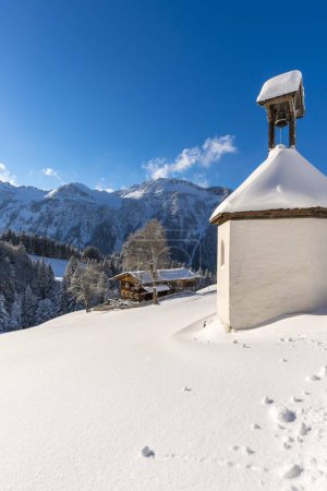 Ferme de montagne et chapelle en hiver, à Gerstruben, un ancien village agricole de montagne dans la vallée de Dietersbach près d'Oberstdorf, derrière l'Himmelschrofenzug, Alpes Allgaeuer, Allgaeu, Bavière, Allemagne.