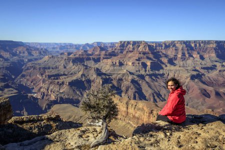 Young woman, tourist sitting at the edge of the gorge of the Grand Canyon, Colorado River, eroded rock landscape, South Rim, Grand Canyon National Park, Arizona, USA, North America