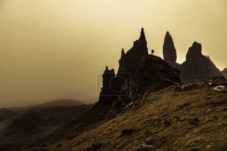 Rock Old Man of Storr backlit with photographer on rock, Portree, Isle of Sky, Scotland, United Kingdom, Europe