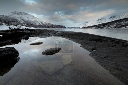 Costa rocosa negra en una bahía en el Ullsfjord, Laksvelbukt, Troms, Noruega, Europa 