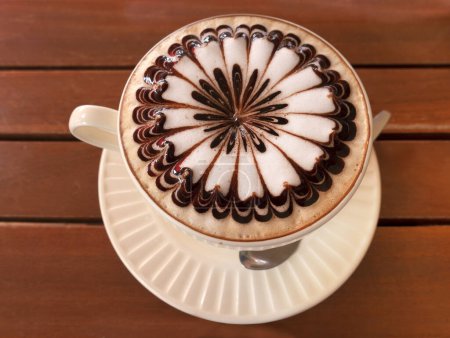 Latte Art, Cappuccino mit kunstvoll dekoriertem Milchschaum in der Tasse auf Holztisch, Bangkok