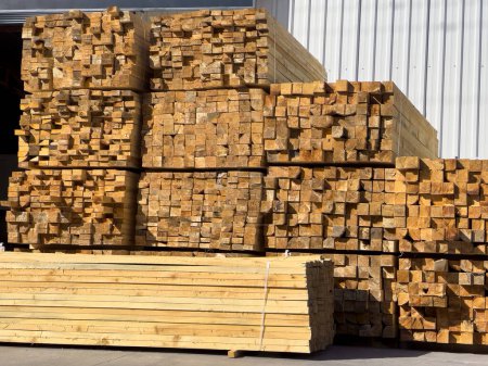 Timbers stacked on top of each other in front of the warehouse. Wooden beam