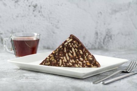 Téléchargez les photos : Gâteau mosaïque chocolat aux noix sur une assiette en porcelaine blanche sur fond de pierre - en image libre de droit