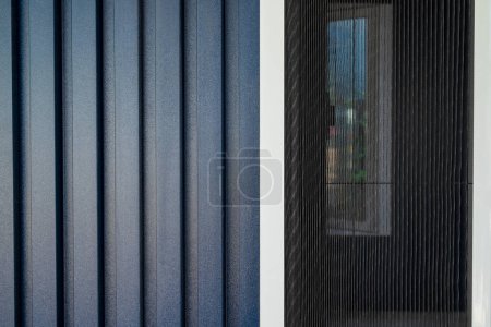 Téléchargez les photos : Maison avec une façade couverte de panneaux en PVC bleu foncé et moustiquaire appliquée aux fenêtres - en image libre de droit
