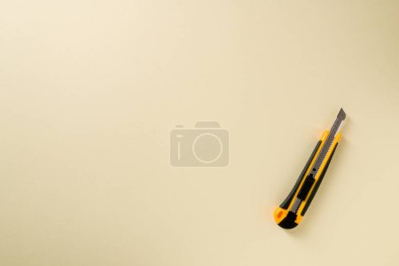 Foto de Cuchillo utilitario con mango amarillo y negro sobre fondo amarillo - Imagen libre de derechos