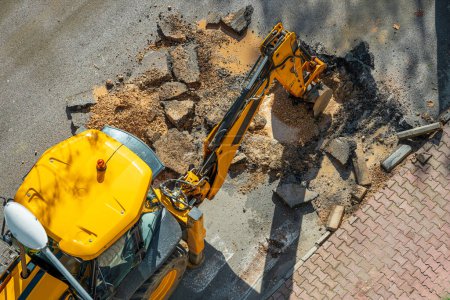Excavadora excavando asfalto para reparar una falla de agua en una calle