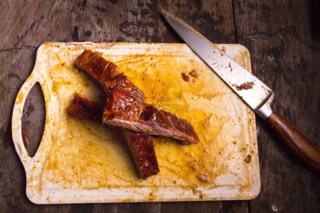 Téléchargez les photos : Côtes de porc fumées sur une planche à découper avec couteau à droite. - en image libre de droit