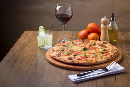 Photo for Pizza Marguerita made with tasty pizza dough, Mozzarella, tomatoes, marjoram and green olives. On the wooden board. Napolitan Pizza. Glass of Red Wine, olive oil, pepper grinder. 2 - Royalty Free Image