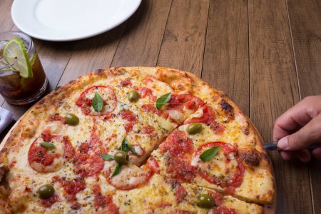 Téléchargez les photos : Pizza à la marguerite à base de mozzarella, fromage, tomate, mayonnaise et olives vertes. Pizza napolitaine traditionnelle. Trancher servi avec du cola soda pour accompagner. - en image libre de droit