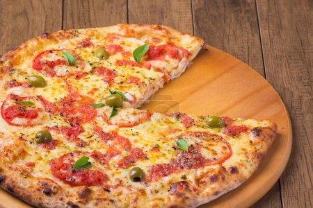 Téléchargez les photos : Pizza à la marguerite à base de mozzarella, fromage, tomates, macaronis et olives vertes. Pizza napolitaine traditionnelle. Pizza manquant une tranche. - en image libre de droit