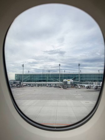 Delantal y edificio del aeropuerto en Munich Aeropuerto MUC, Alemania visto a través de la ventana de un avión