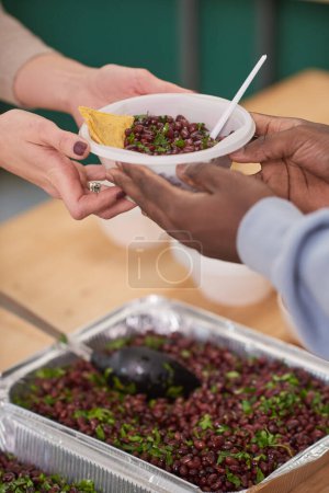 Foto de Vertical medio primer plano de voluntario irreconocible dando comida a los pobres en la cantina de caridad - Imagen libre de derechos