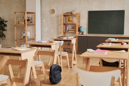 Téléchargez les photos : Image de fond de la salle de classe moderne de l'école avec des bureaux en bois dans la rangée face au tableau noir, pas de personnes, espace de copie - en image libre de droit