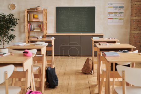 Foto de Imagen de fondo de gran angular de escritorios escolares de madera en fila frente a pizarra en aula vacía, espacio para copiar - Imagen libre de derechos