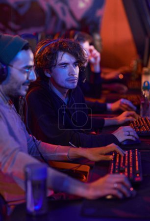 Photo for Concentrated young man sitting in esports bar and watching how guy completing game level - Royalty Free Image