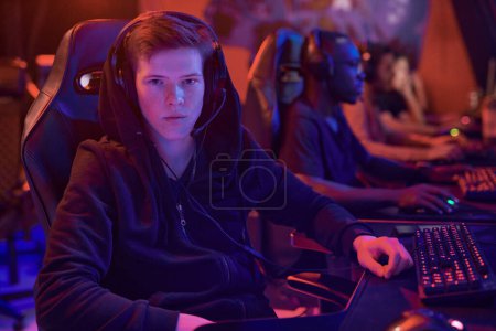 Photo for Portrait of serious young Caucasian guy in headset with microphone sitting in comfortable chair in esports club - Royalty Free Image