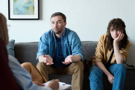 Foto de Joven hablando con el psicólogo sobre problemas con su esposa durante la sesión en la oficina - Imagen libre de derechos