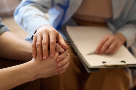 Photo for Close-up of therapist supporting her patient at session holding his hand and talking to him - Royalty Free Image