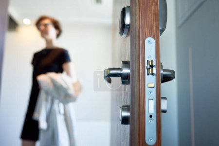 Foto de Primer plano de cerradura y manija de la puerta, mujer de negocios que viene en el apartamento en el fondo - Imagen libre de derechos