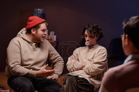 Téléchargez les photos : Plan horizontal de deux jeunes hommes caucasiens modélisant la situation pendant la psychothérapie de groupe dramatique - en image libre de droit