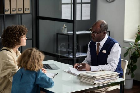 Portrait de l'homme noir senior consultant mère avec enfant dans le bureau de l'agence d'assurance