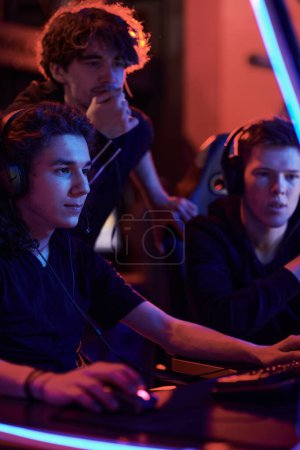 Photo for Group of esports league members attentively looking at computer monitor and performing game mission together - Royalty Free Image