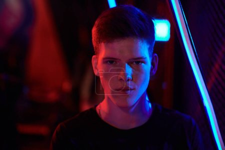 Photo for Portrait of serious young Caucasian guy standing in red and blue light, cybersport gamer - Royalty Free Image