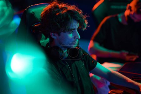 Photo for Serious young Caucasian guy with headphones around neck playing online game in esports league - Royalty Free Image