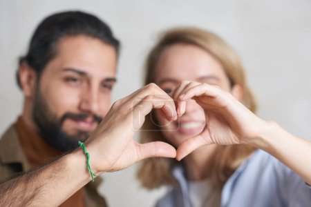 Photo for Close-up shot of handsome young man and attractive blond woman doing hand heart gesture together - Royalty Free Image