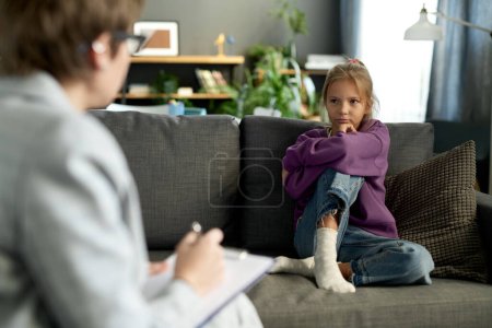 Niña sentada en el sofá en la sala de estar y conversando con el psicólogo