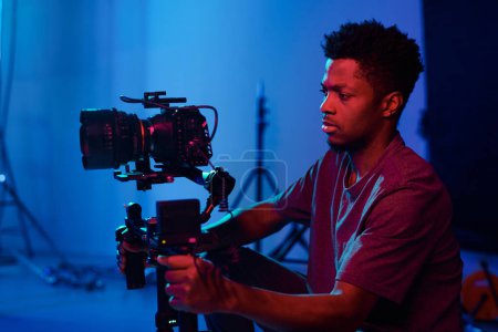 Foto de Operador afroamericano concentrándose en su trabajo, que utiliza la cámara en el set - Imagen libre de derechos