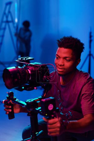 Foto de Operador de cámara afroamericano usando cámara profesional para grabar proceso en estudio - Imagen libre de derechos