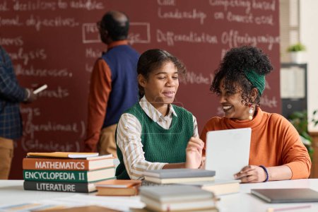 Foto de Retrato de dos niñas negras alegres riendo mientras disfrutan de las tareas escolares en el espacio de copia del aula de la universidad - Imagen libre de derechos