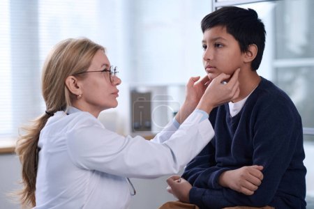 Side view portrait of female pediatrician examining young boy during health check up in clinic