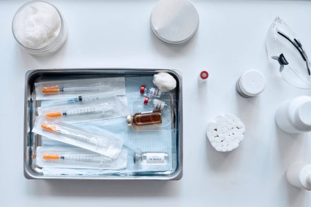 Minimale Draufsicht auf medizinische Schale mit Impfstoffen und Spritzen im Kopierraum der Klinik