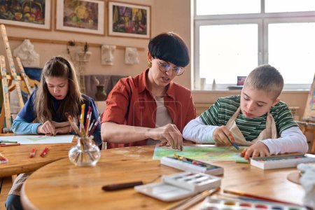 Retrato de una maestra que ayuda a niños con discapacidad a disfrutar de la pintura en un estudio de arte
