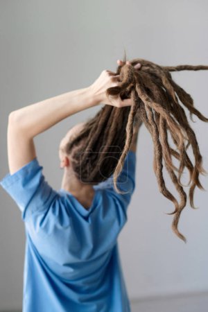Photo for Vertical back view of Caucasian woman holding long dreadlocks out to camera minimal - Royalty Free Image
