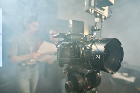 Background image of professional digital video camera on stand in video production studio with smoke effect copy space