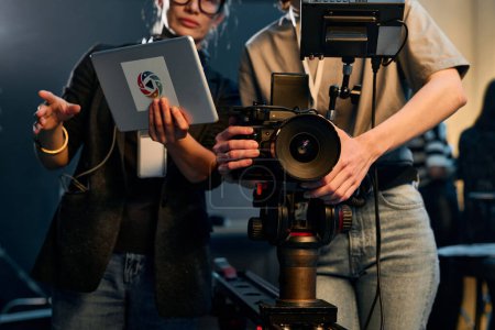 Schriftbild abgeschnittene Aufnahme von zwei Frauen, die eine professionelle Videokamera bedienen und in einem Filmteam am Set arbeiten