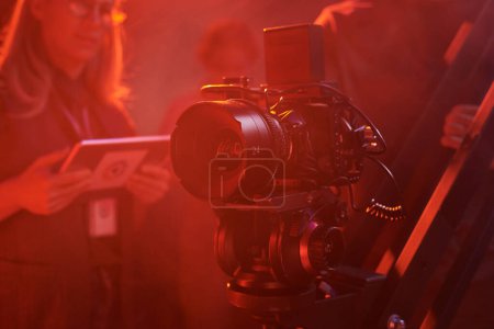 Close up background image of pro videocamera equipment on set in red neon lights, copy space