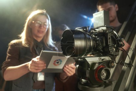 Pro video camera with female director overseeing video production, copy space
