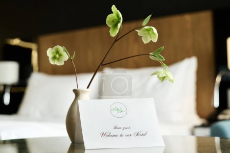Close up background image of delicate floral decor in hotel room with welcome note on table copy space